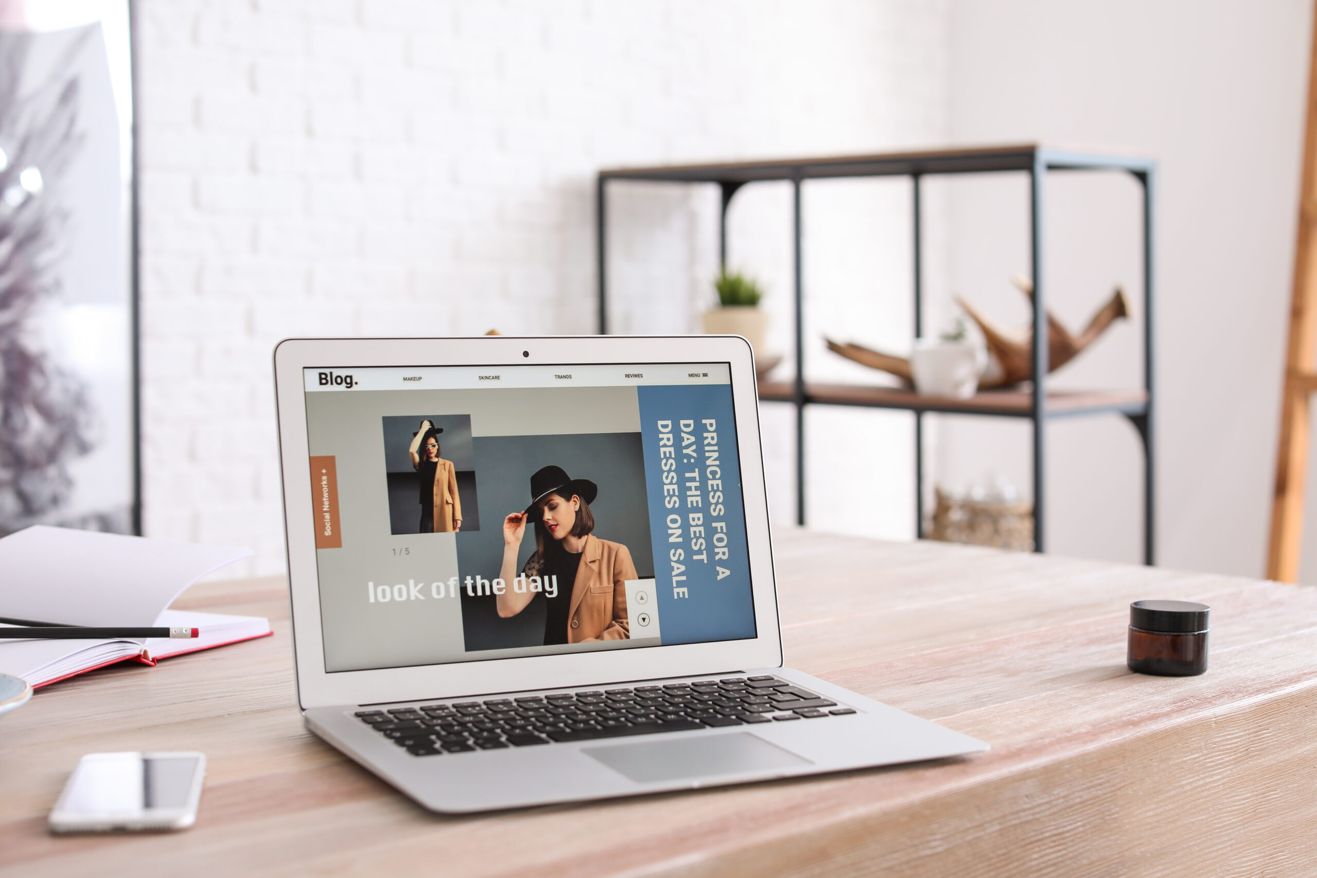 Laptop with open page of fashion blog on table