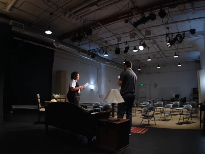 2 people standing in an empty Black Box Theater